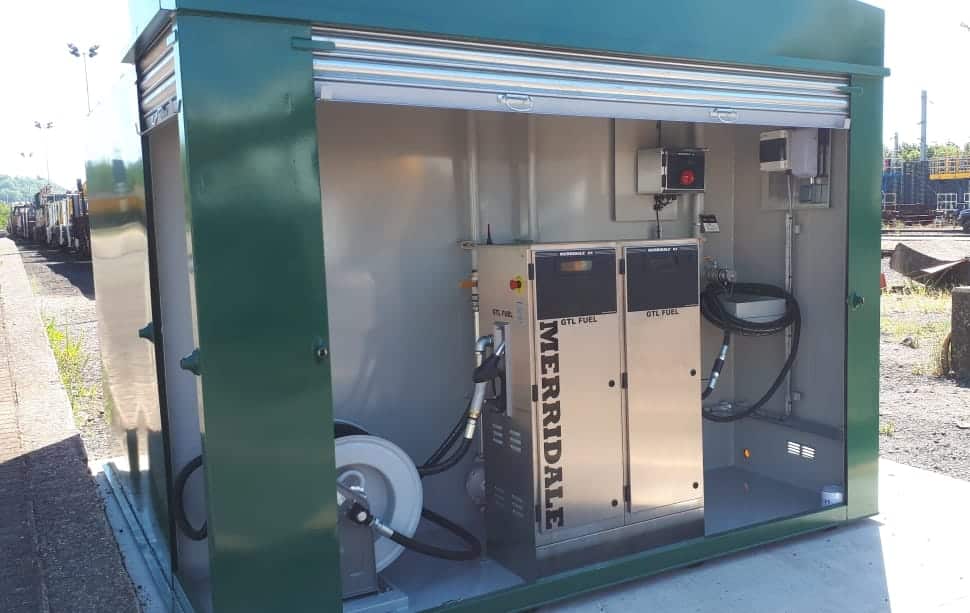 A close-up shot of an outdoor green Merridale commercial fuel storage tank featuring an open roller-shutter cabinet compartment. Inside, a twin-cabinet stainless steel fuel dispenser labeled "GTL FUEL" is installed alongside a heavy-duty hose reel and integrated wall-mounted control systems.