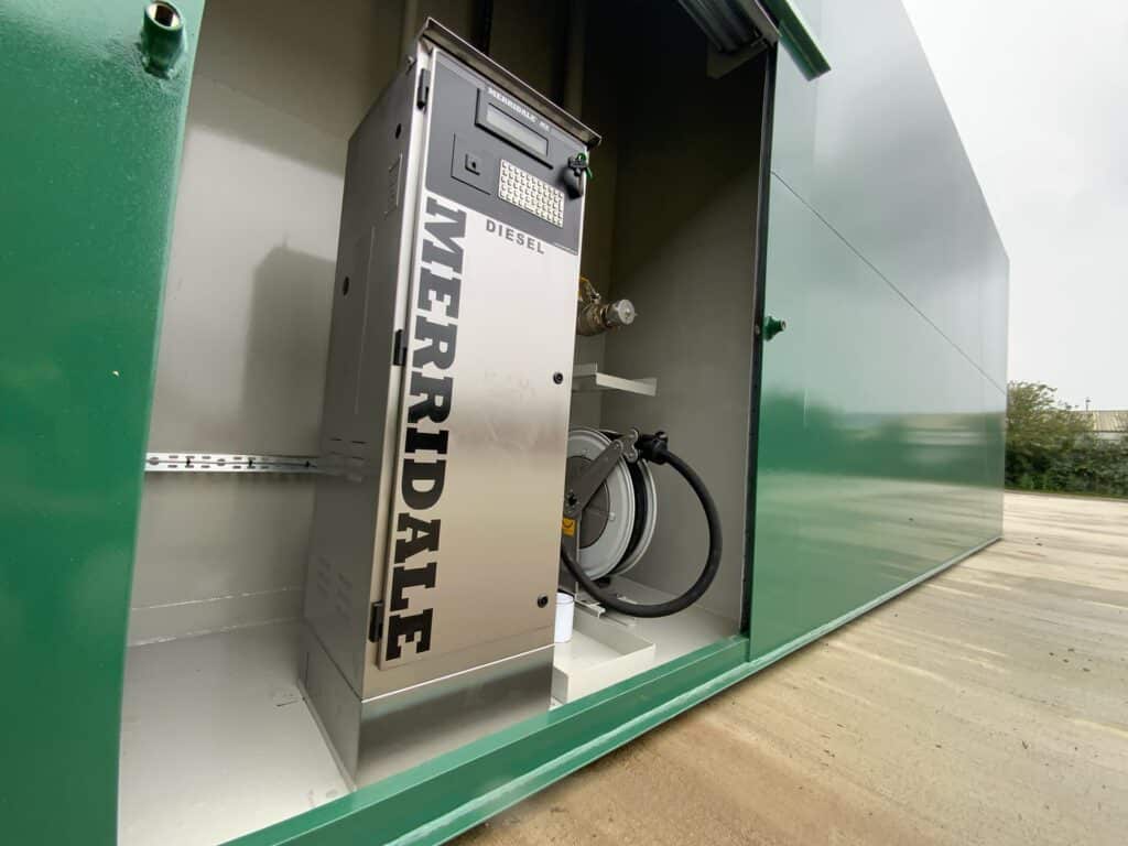 A stainless steel Merridale MX diesel pump and integrated hose reel housed inside a secure, green metal industrial enclosure. The unit features a digital display and keypad for fuel management.