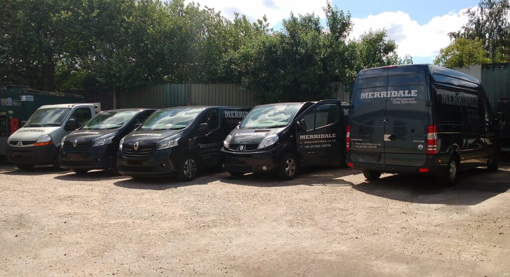 A row of dark blue and silver commercial service vans branded with the Merridale Fuel Management logo parked in a yard on a sunny day.